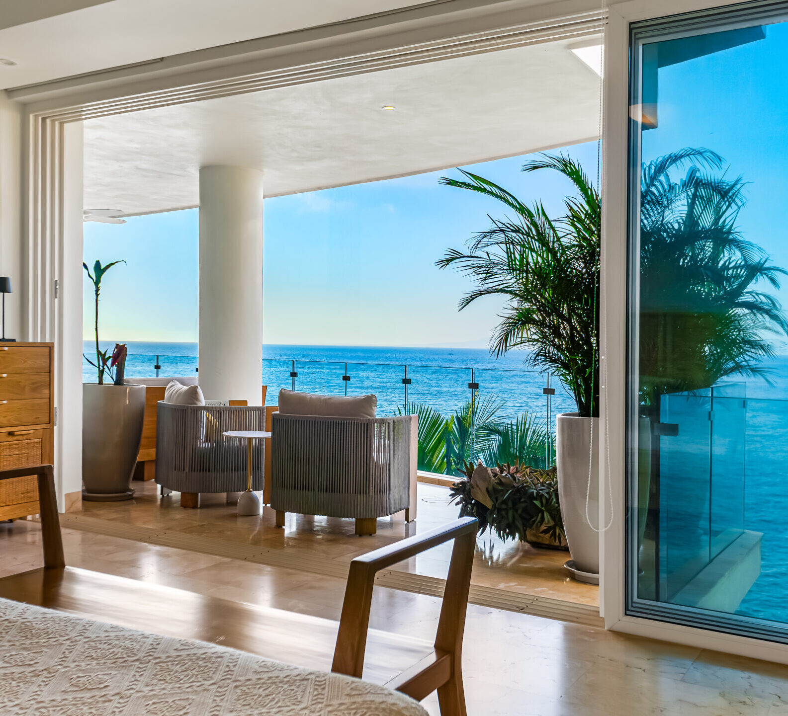 SDM Arco Major 4-22 Oceanfront living area with floor-to-ceiling sliding doors opening to a covered terrace, featuring modern furnishings and panoramic sea views.