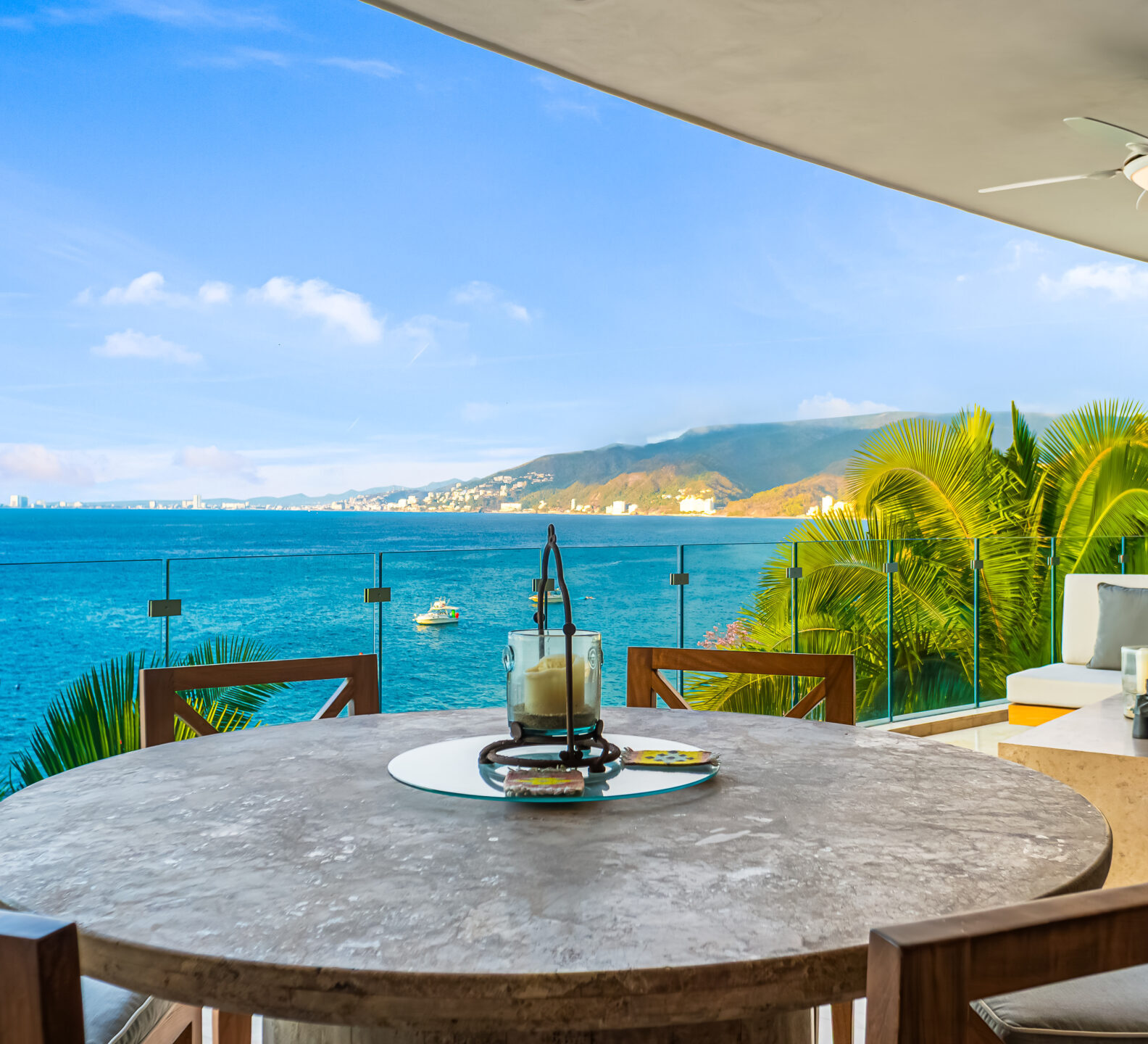 SDM Arco Major 4-34 Round dining table on a covered terrace with panoramic ocean and mountain views. Indoor-Outdoor Dining Area