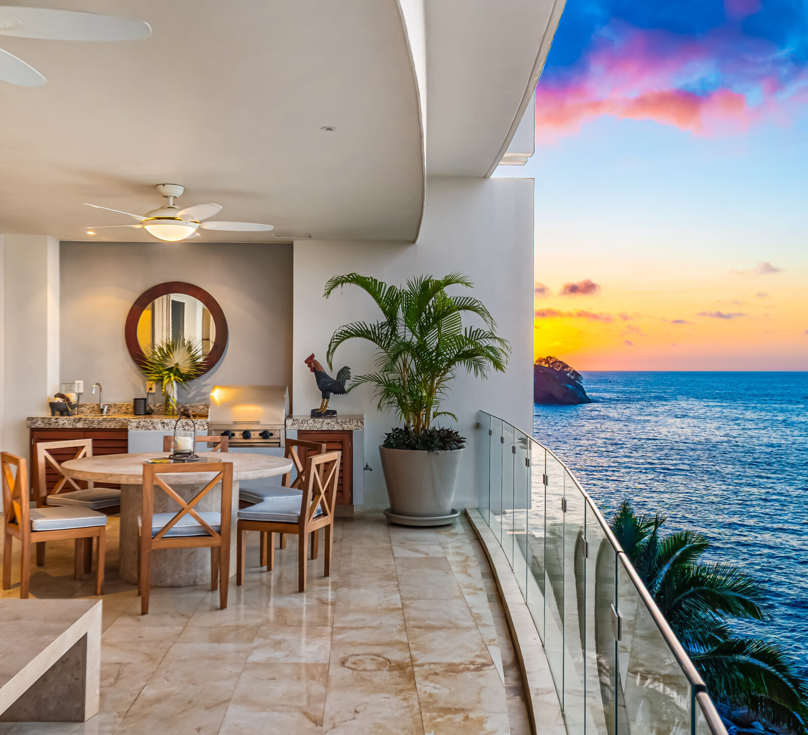 SDM Arco Major 4-55 Outdoor dining table on a covered terrace overlooking the ocean at sunset.