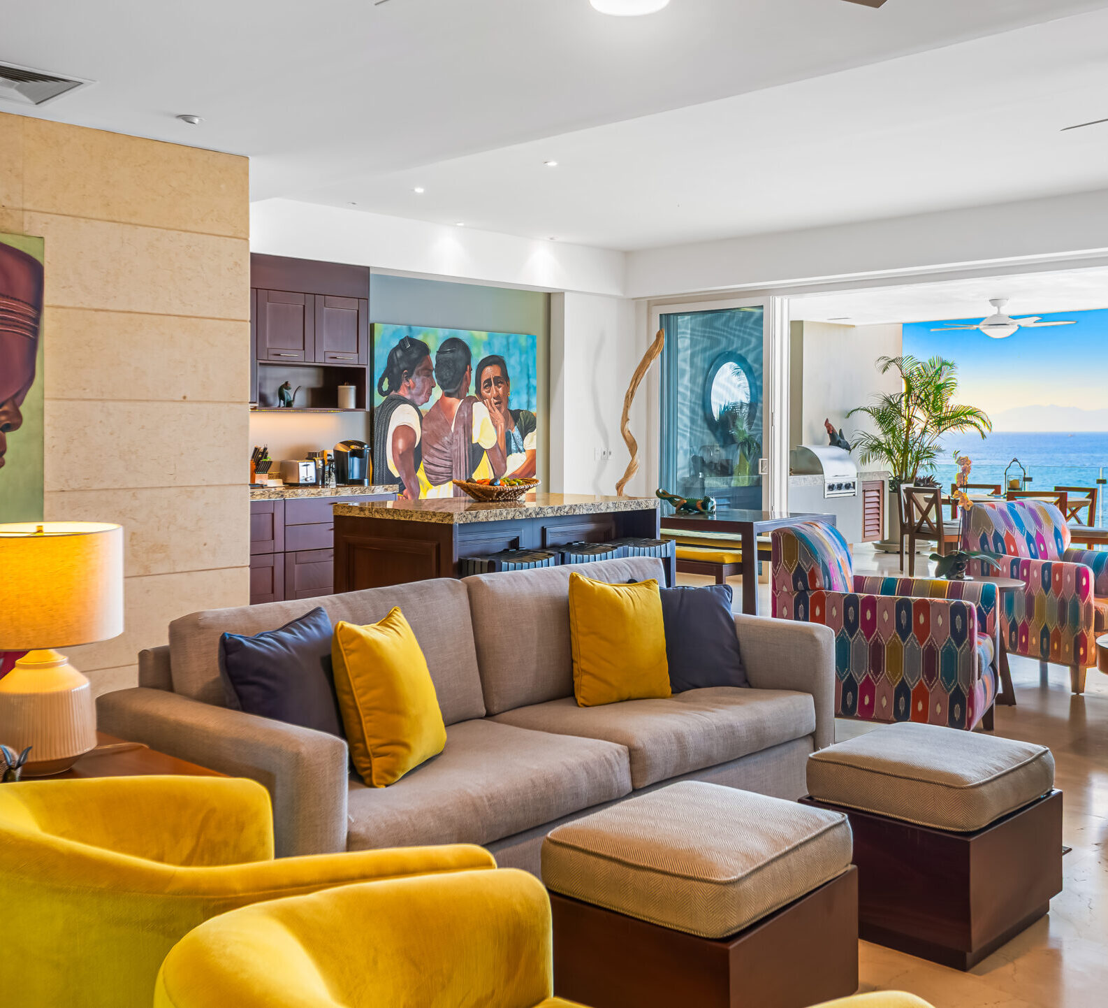 SDM Arco Major 4-7 Comfortable living room with sectional sofa, yellow accent chairs, contemporary artwork, and direct access to a covered terrace overlooking the sea.