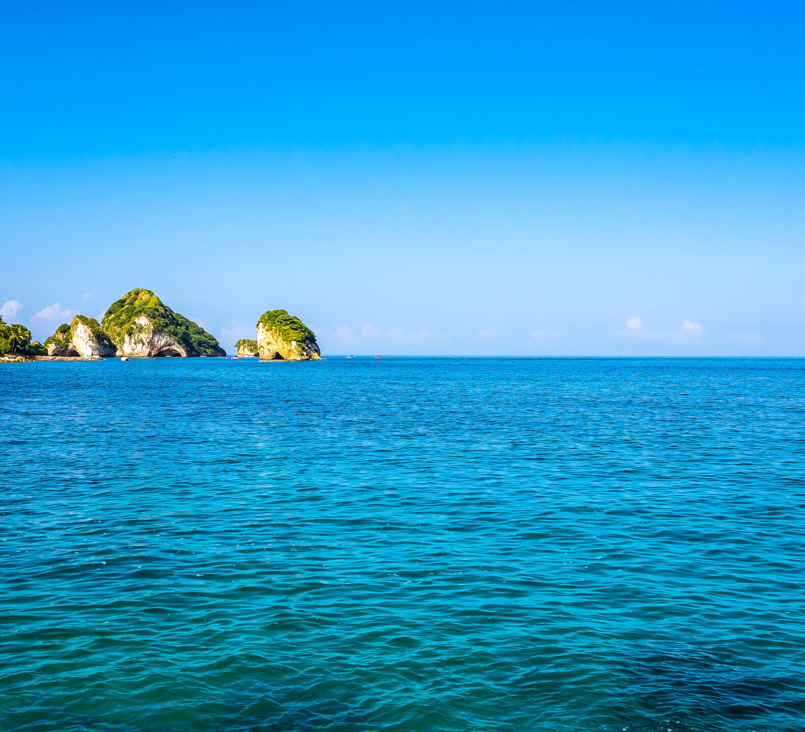 Expansive view of the blue ocean beneath a clear sky with small islands in the distance.