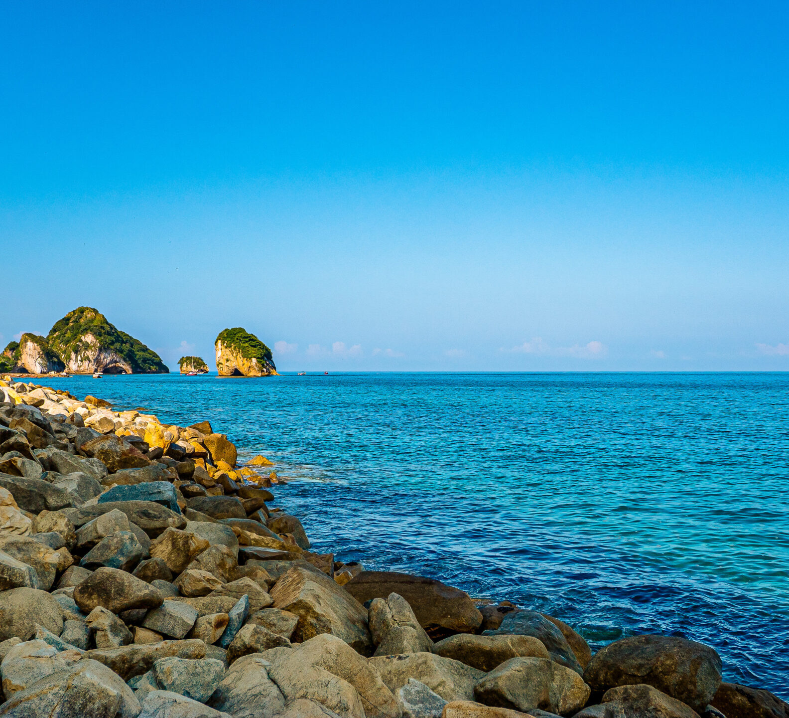 Rocky coastline with turquoise ocean waters and small islands in the distance.