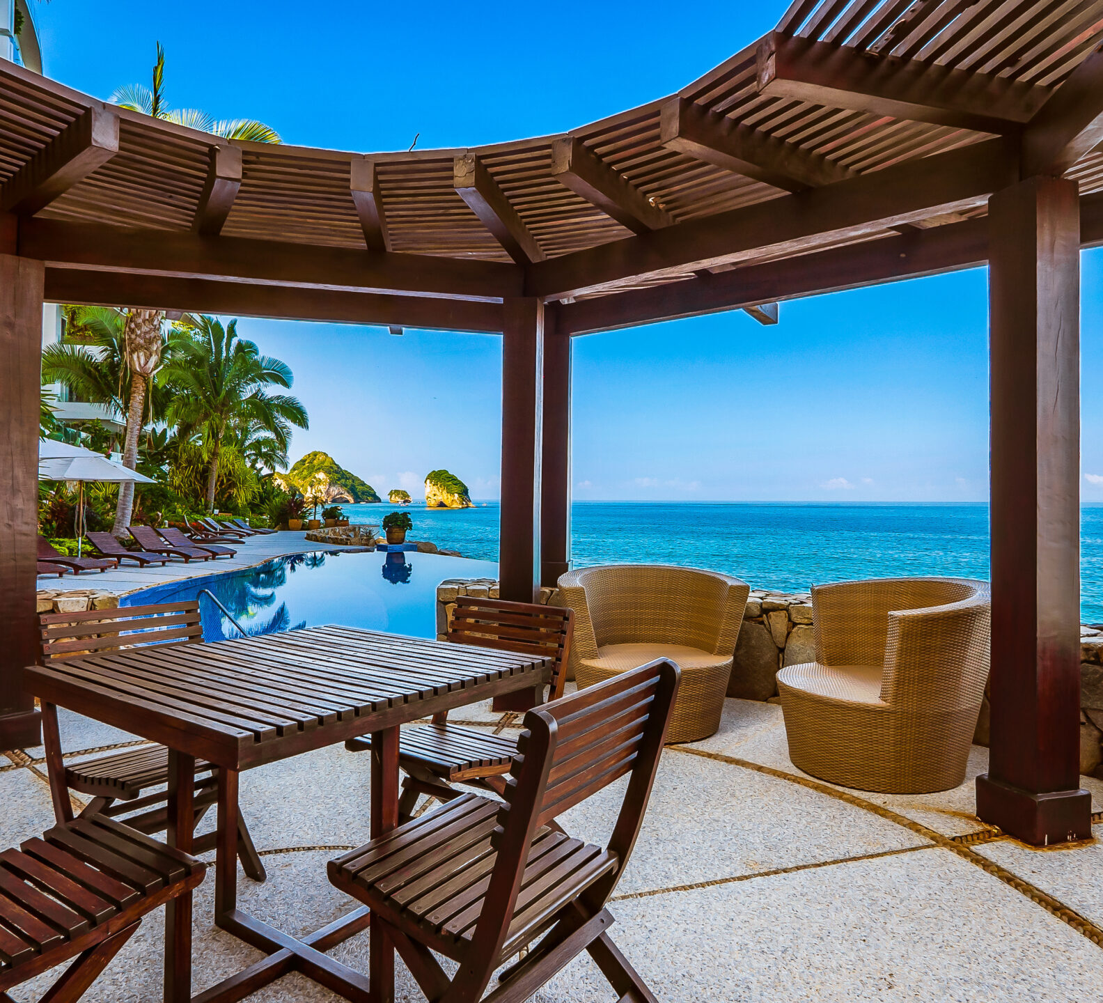 Covered outdoor pavilion with dining furniture and panoramic ocean views.