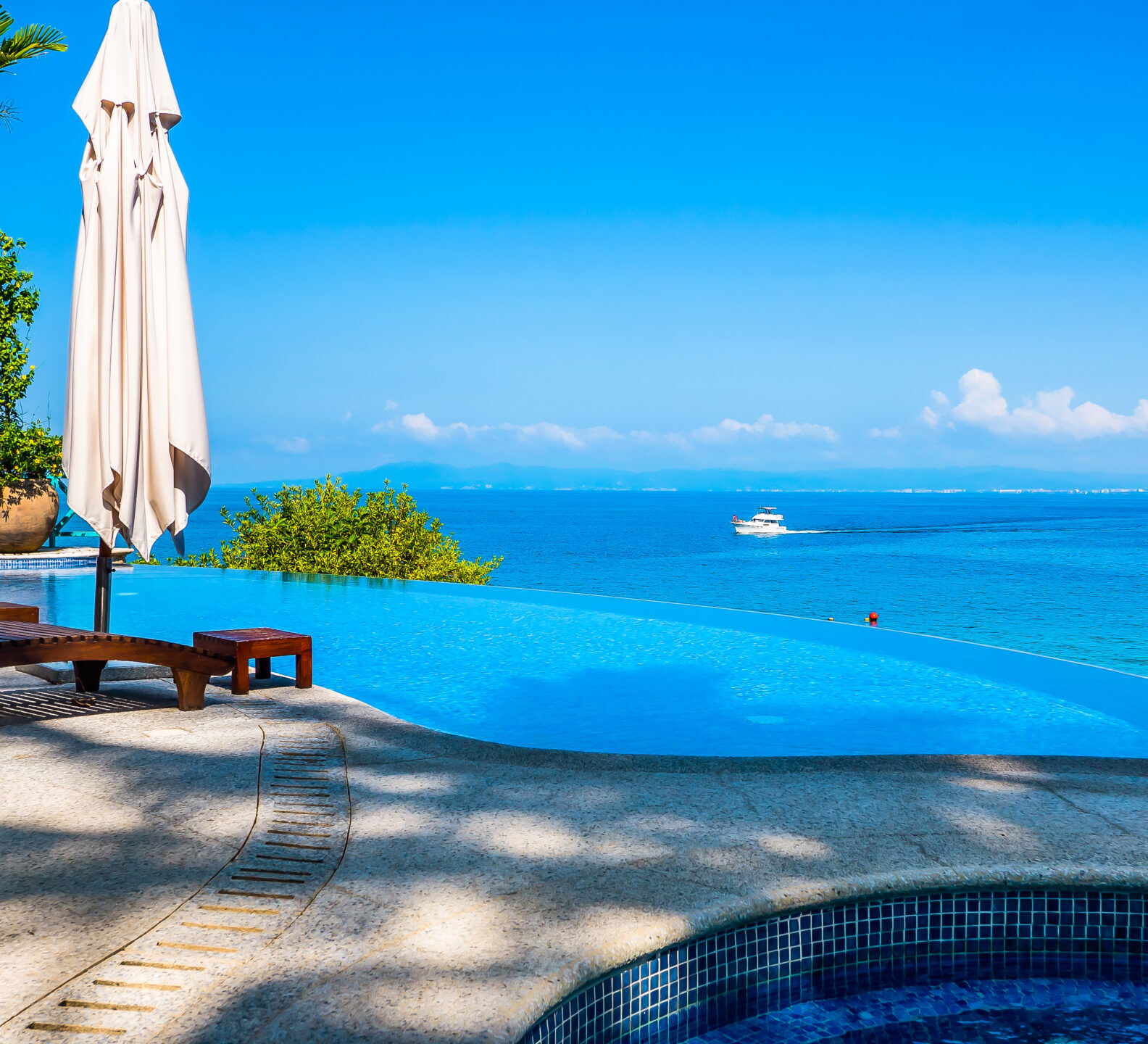 Poolside spa with lounge chairs and sweeping views of the ocean.