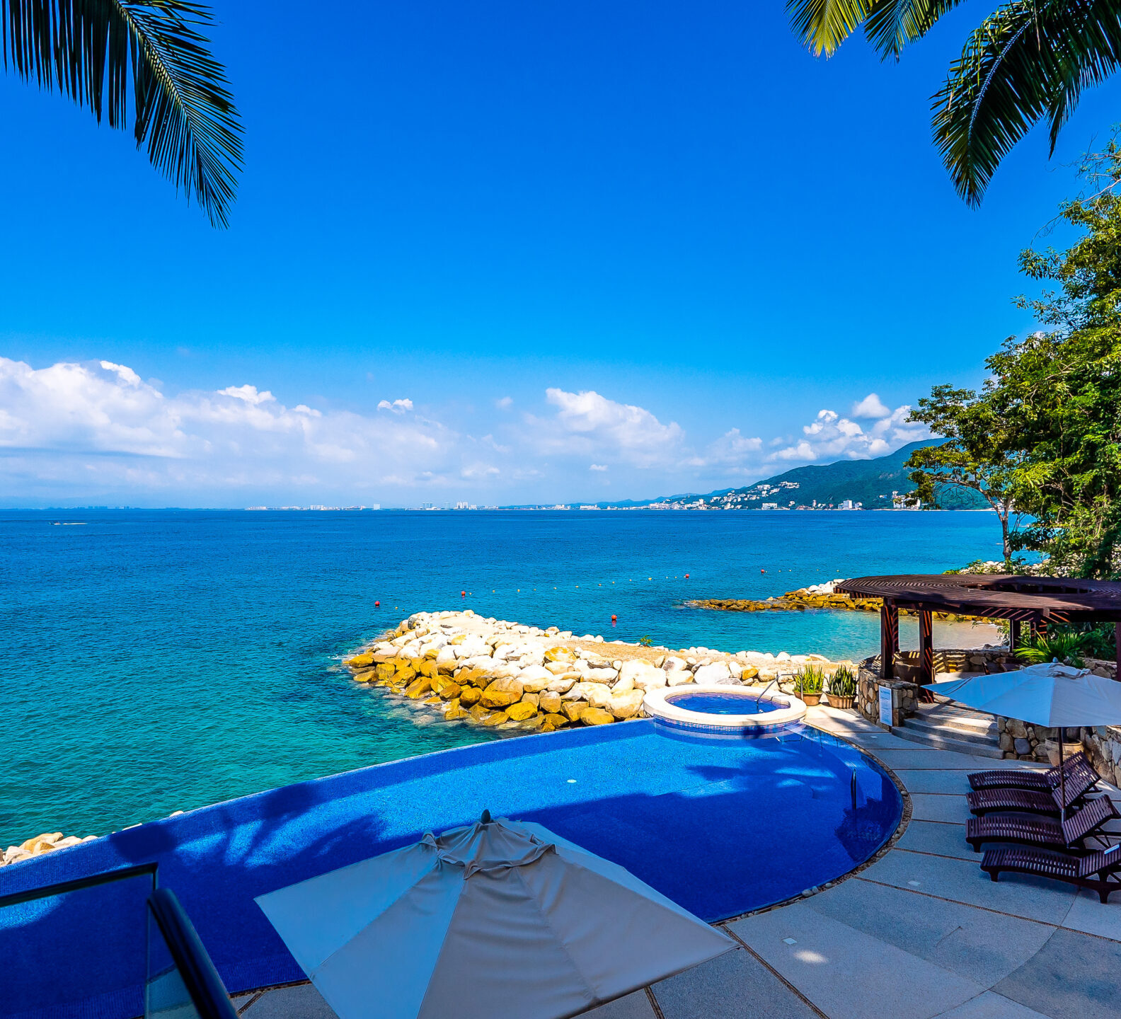 Infinity pool and pool deck overlooking the ocean and rocky shoreline.