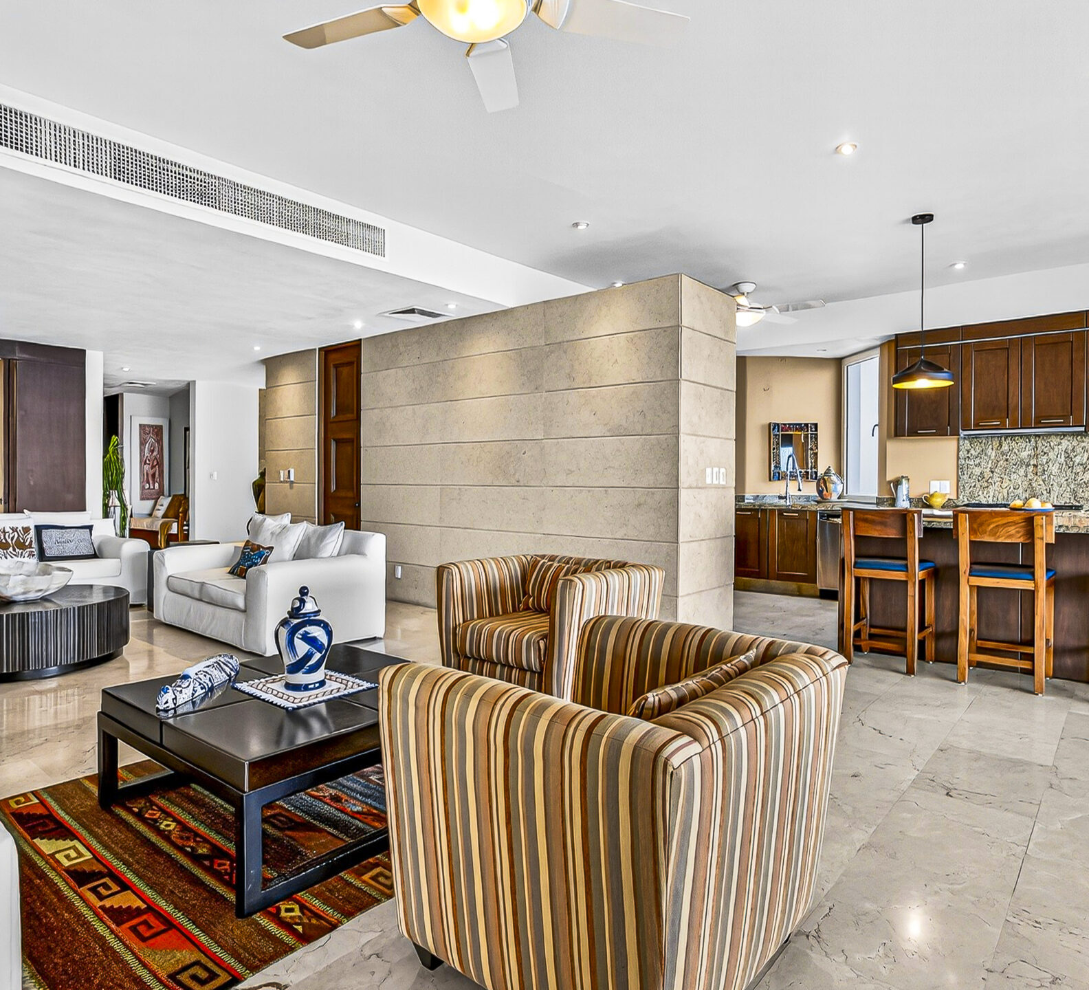 Open-concept great room with seating area and kitchen bar beneath pendant lighting.