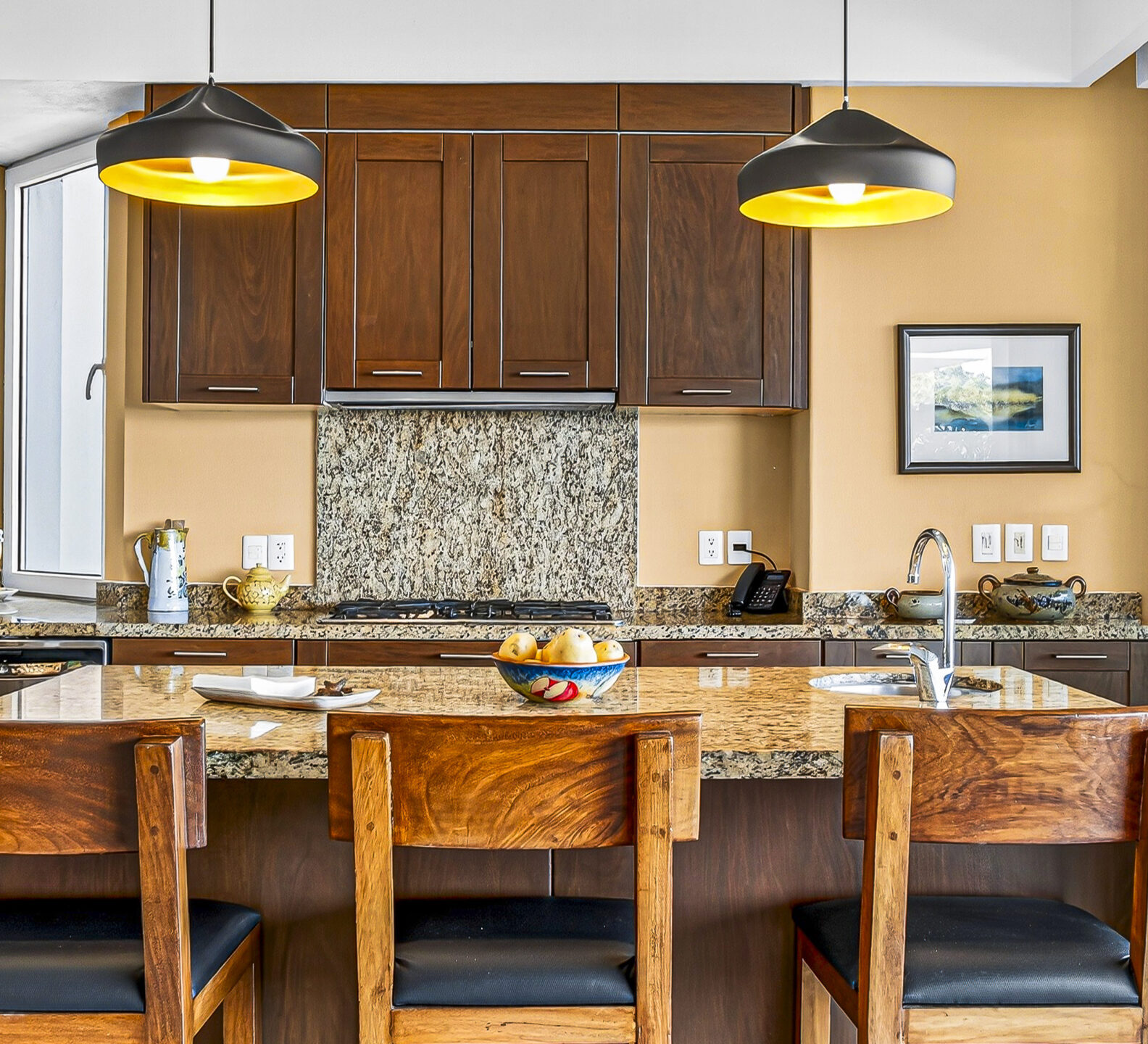 Kitchen island with bar seating, pendant lights, and dark wood cabinetry.