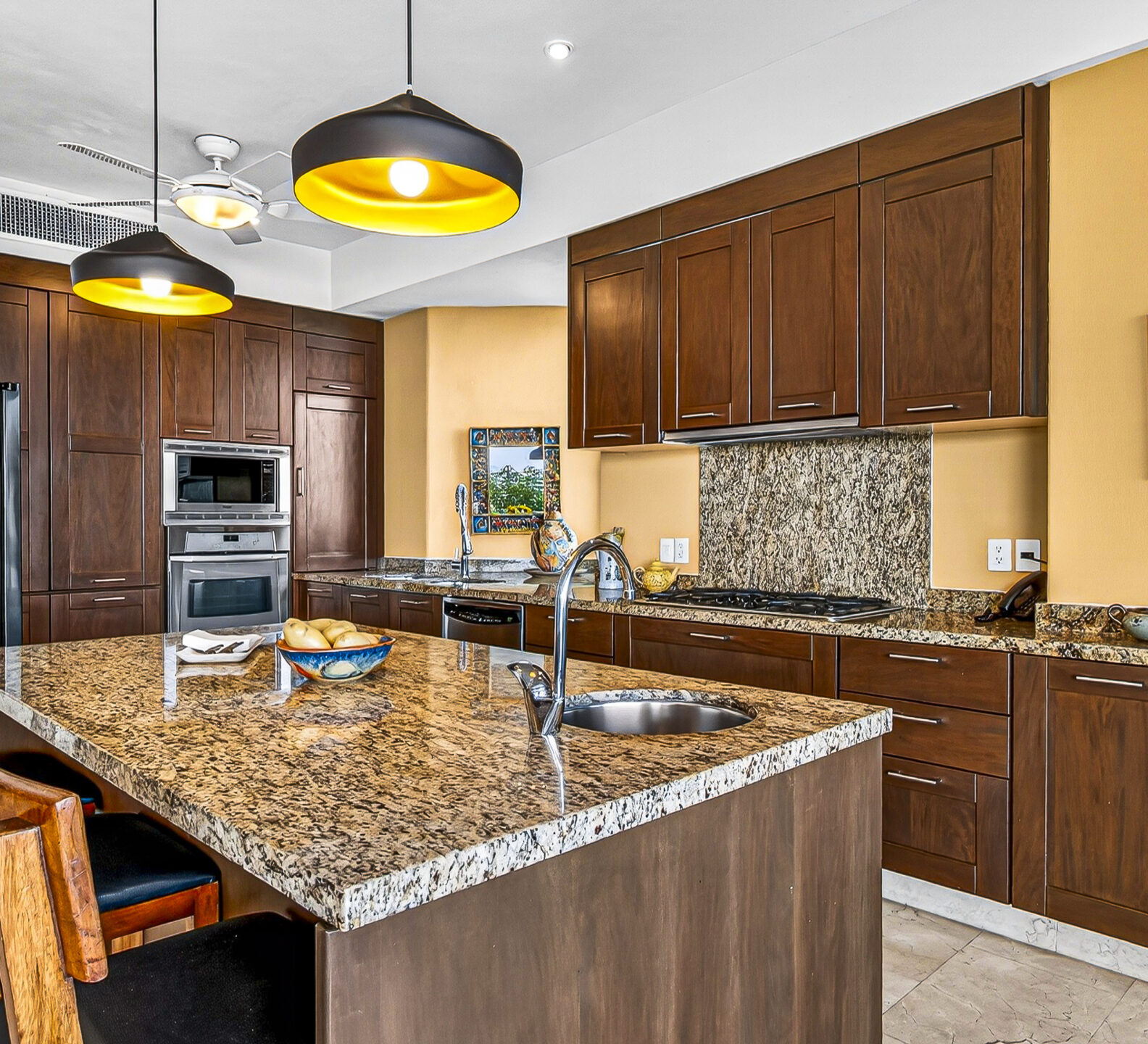 Modern kitchen with granite countertops, custom wood cabinets, and stainless steel appliances.