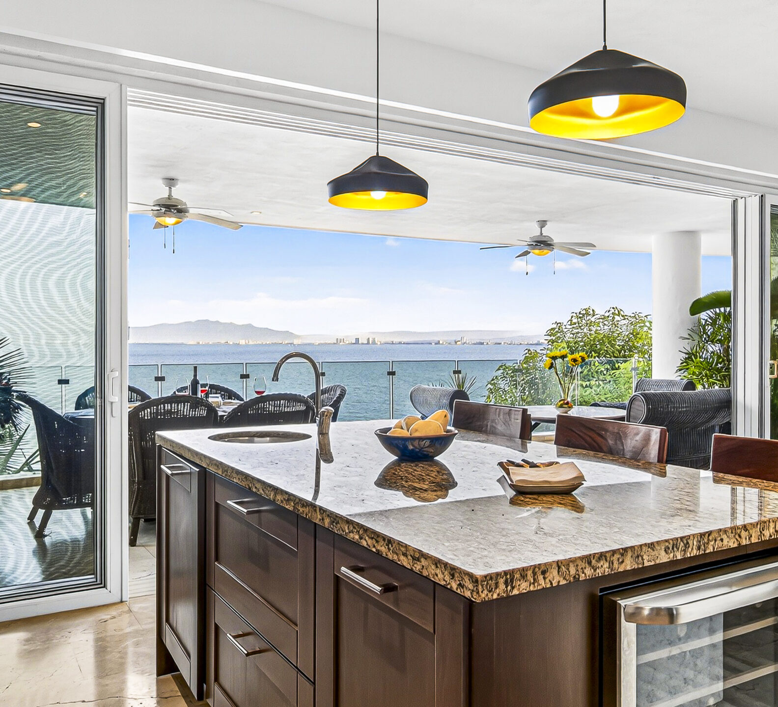 Kitchen island with bar seating and sliding doors opening to an oceanfront terrace.