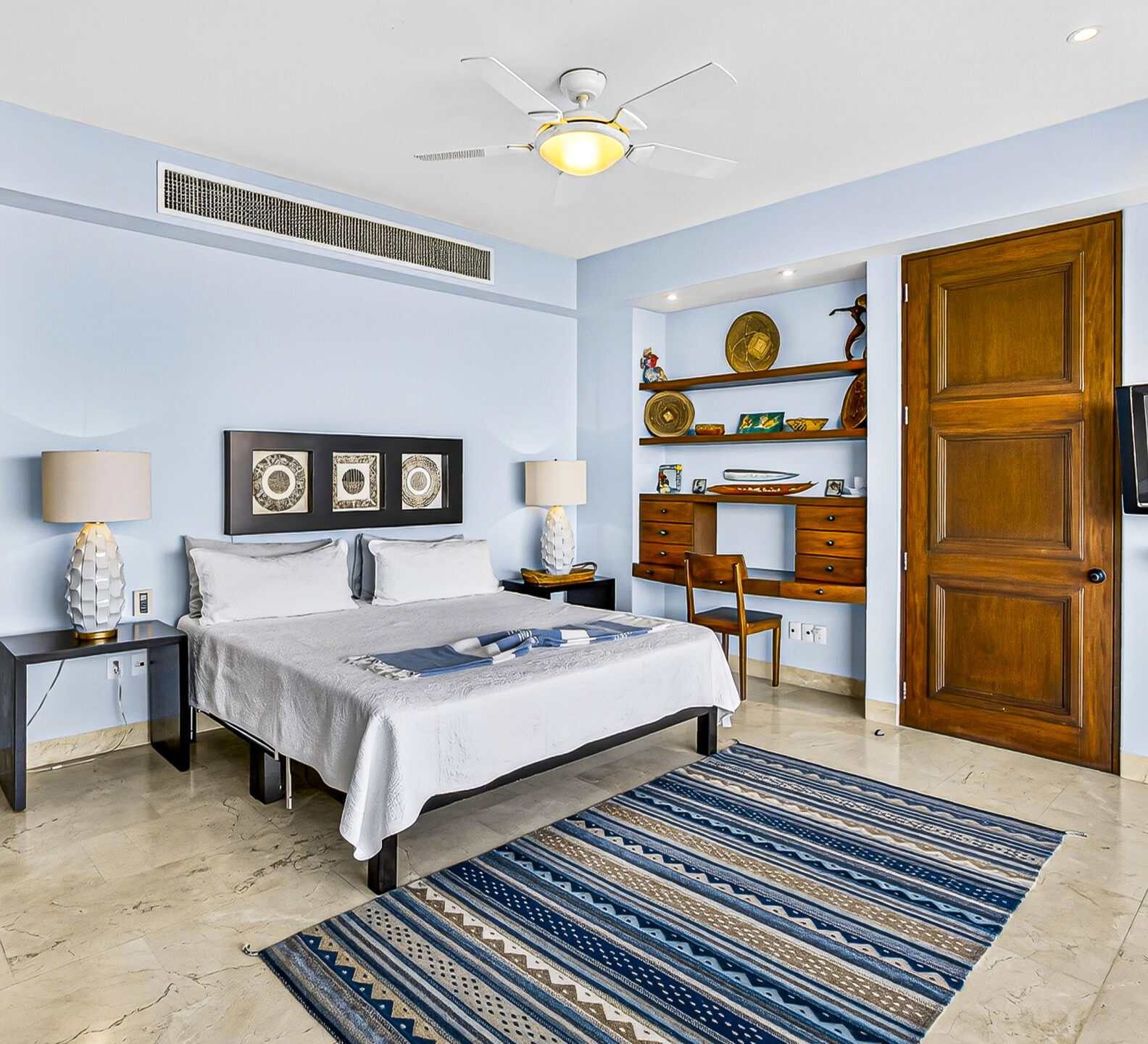 Bedroom with a king-size bed, built-in shelving, and contemporary furnishings.