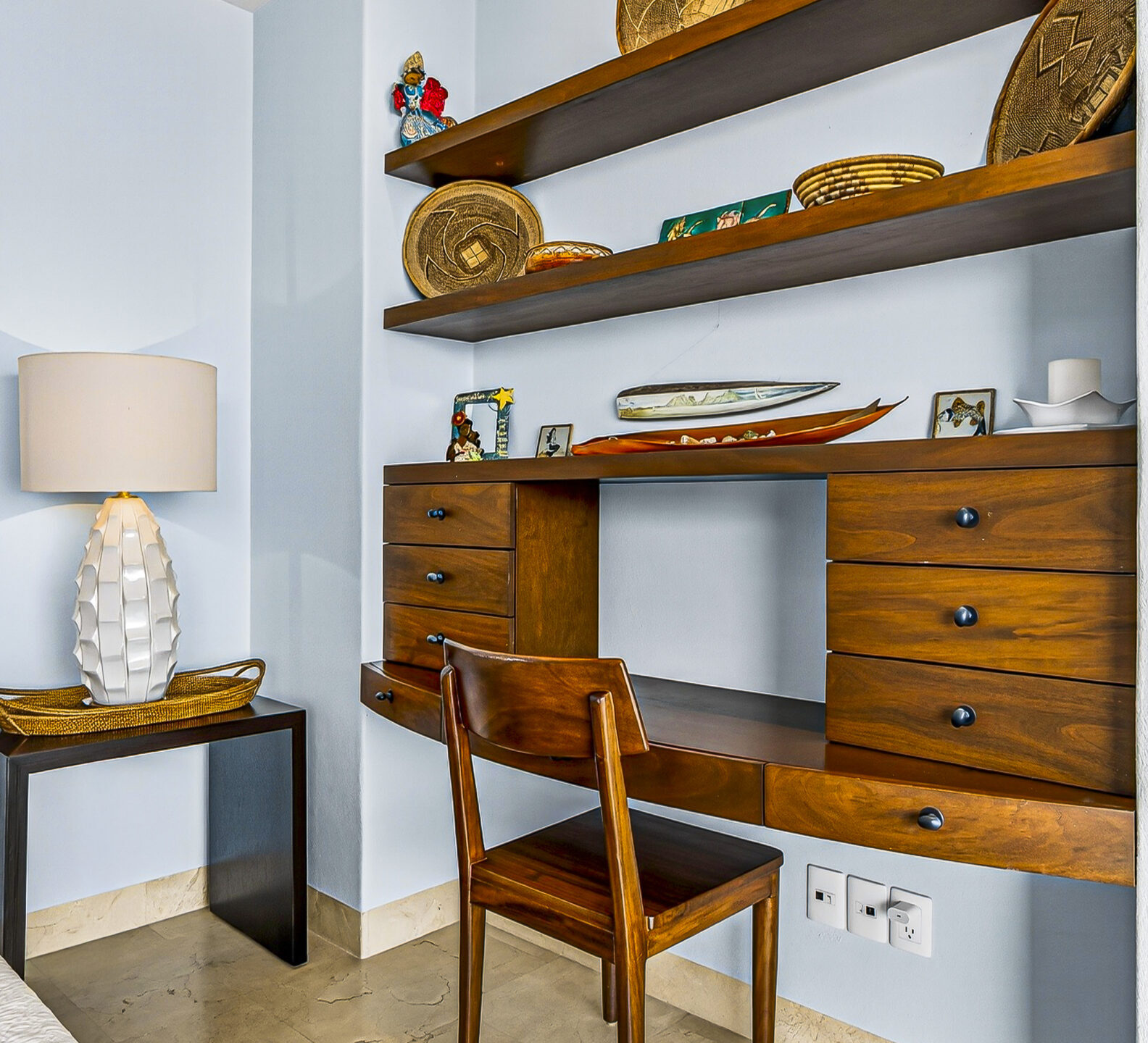 Wood desk with built-in shelves and storage beside a bedroom seating area.