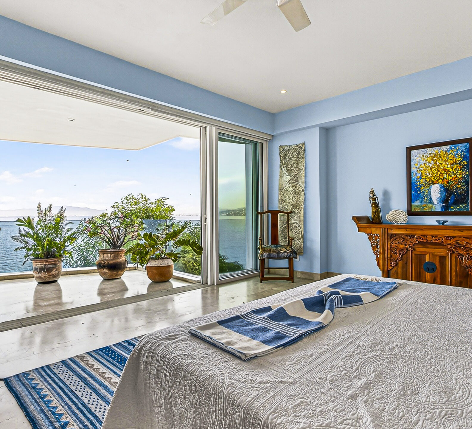 Bright bedroom with panoramic ocean views and sliding doors leading to a private terrace.