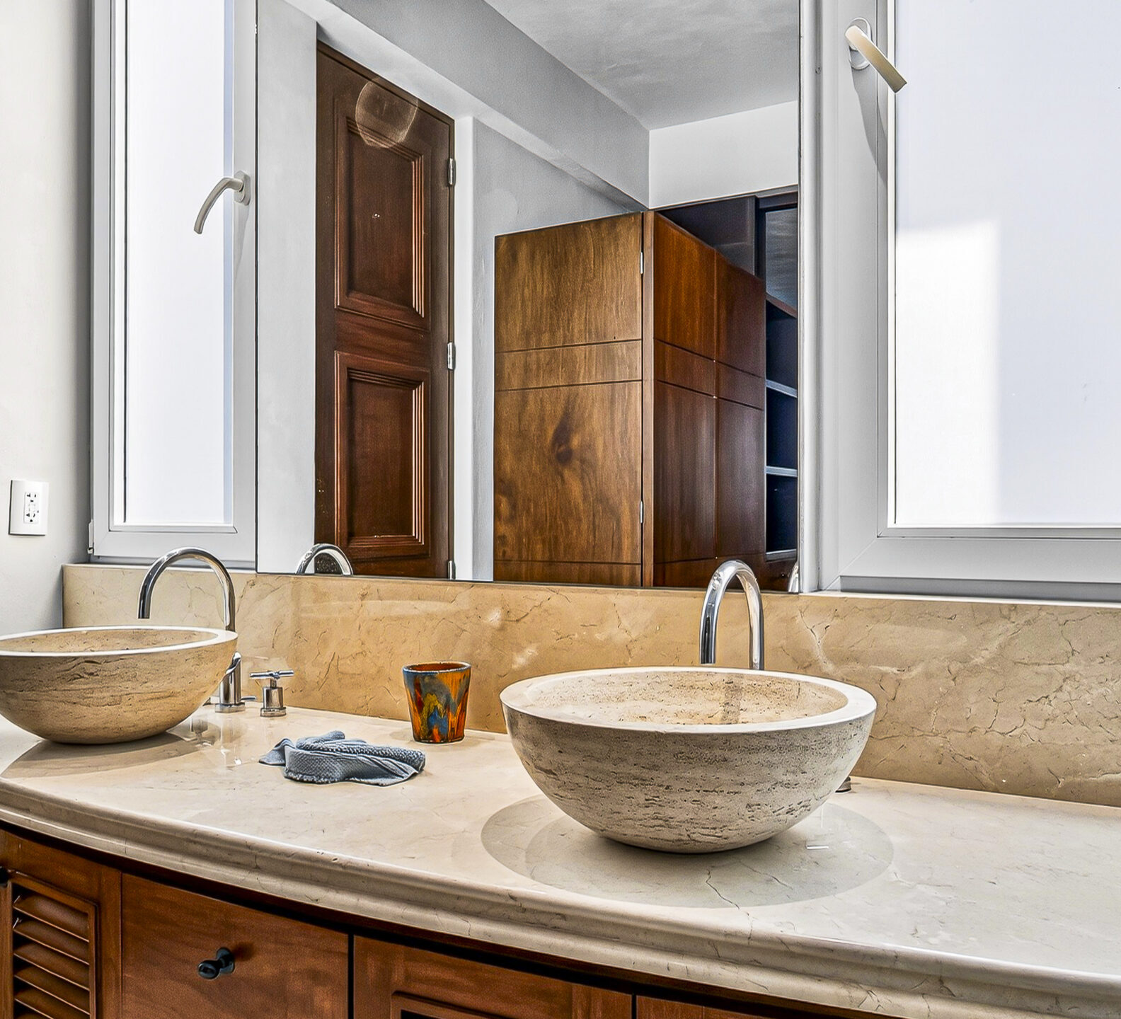 Bathroom with dual vessel sinks, stone countertops, and a large wall mirror.