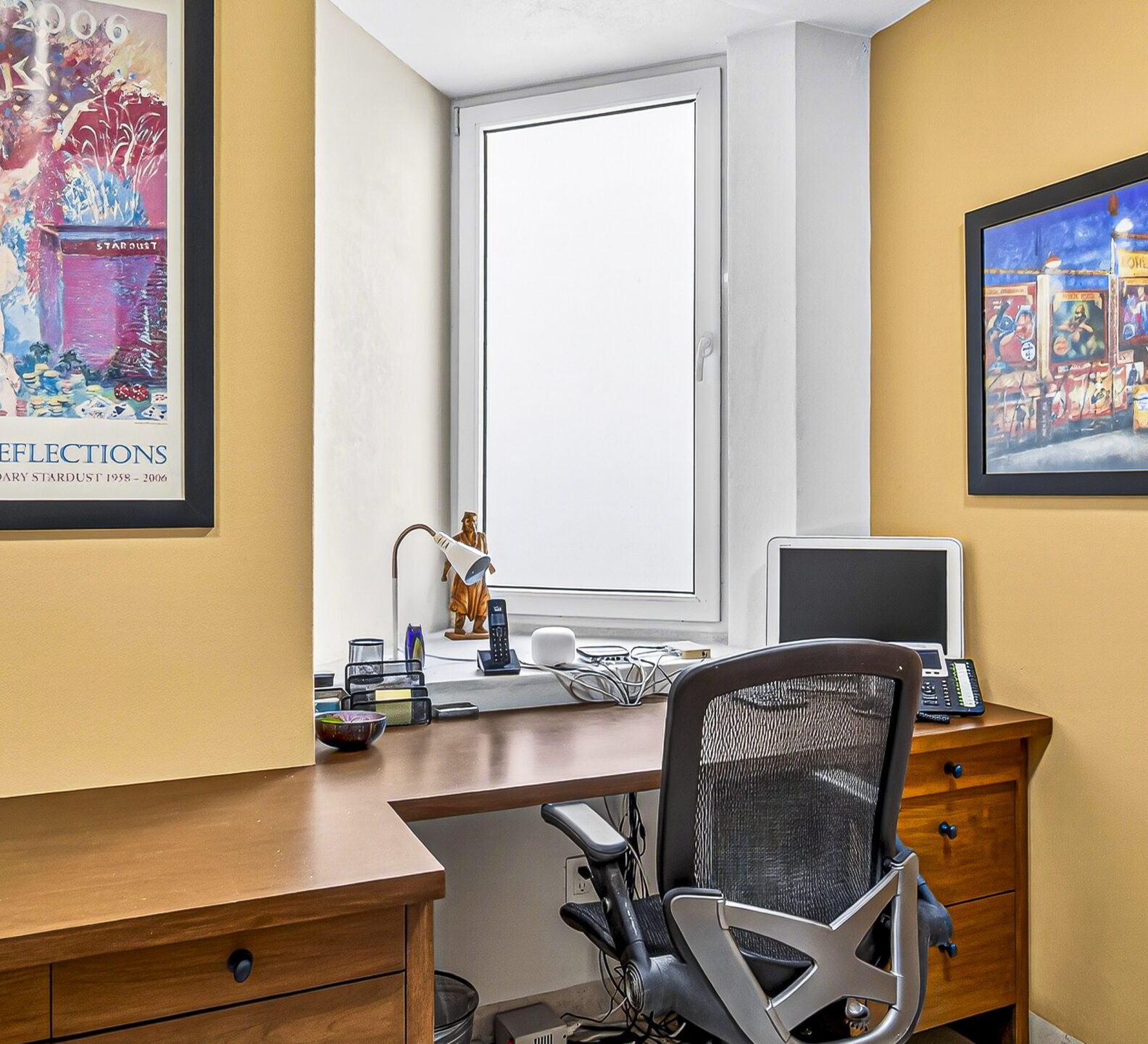 Private office with wood cabinetry, framed artwork, and a workstation.