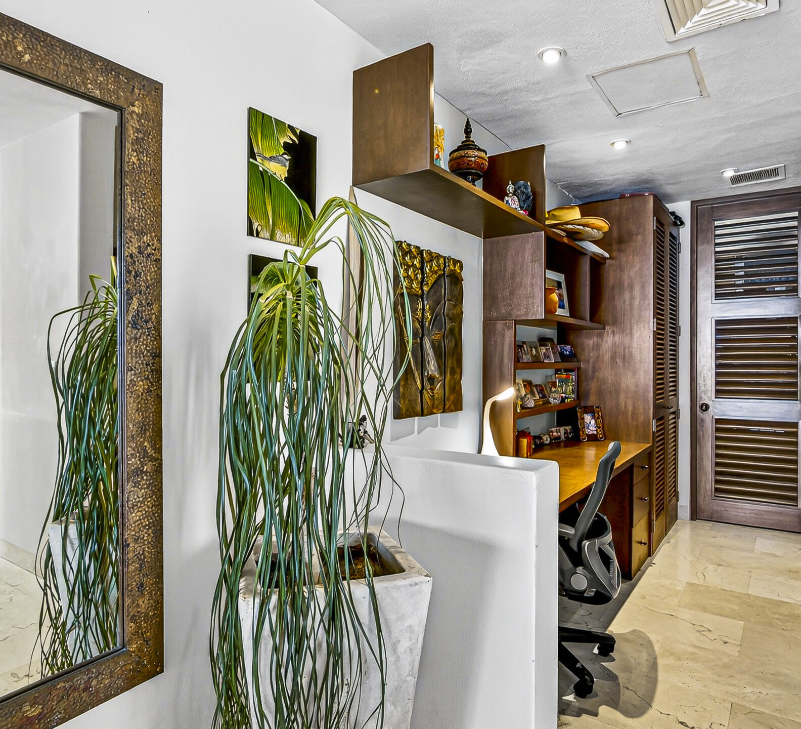 Interior hallway featuring decorative shelving, artwork, and a large framed mirror.