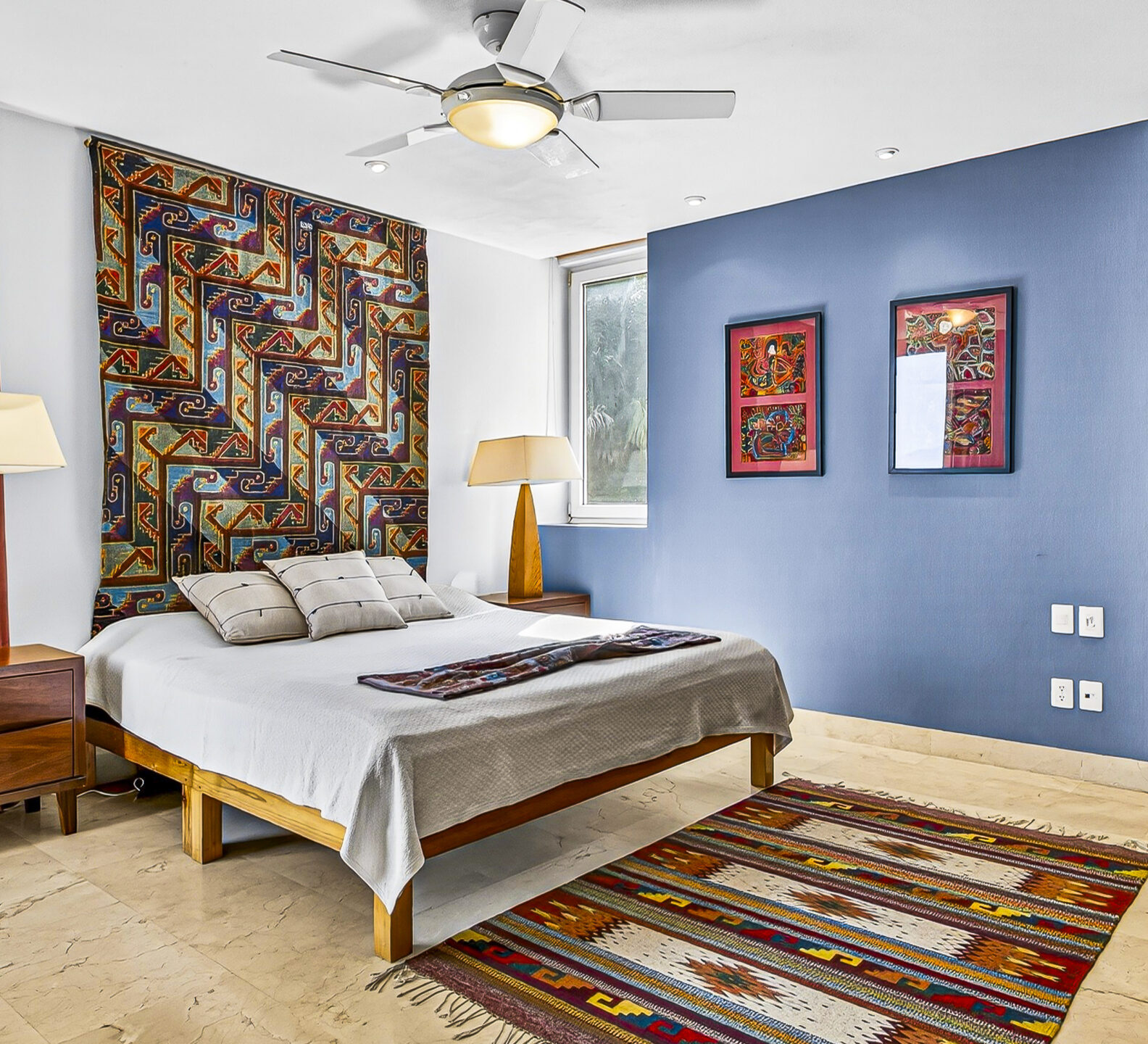 Spacious bedroom with a king-size bed, colorful artwork, and blue accent walls.