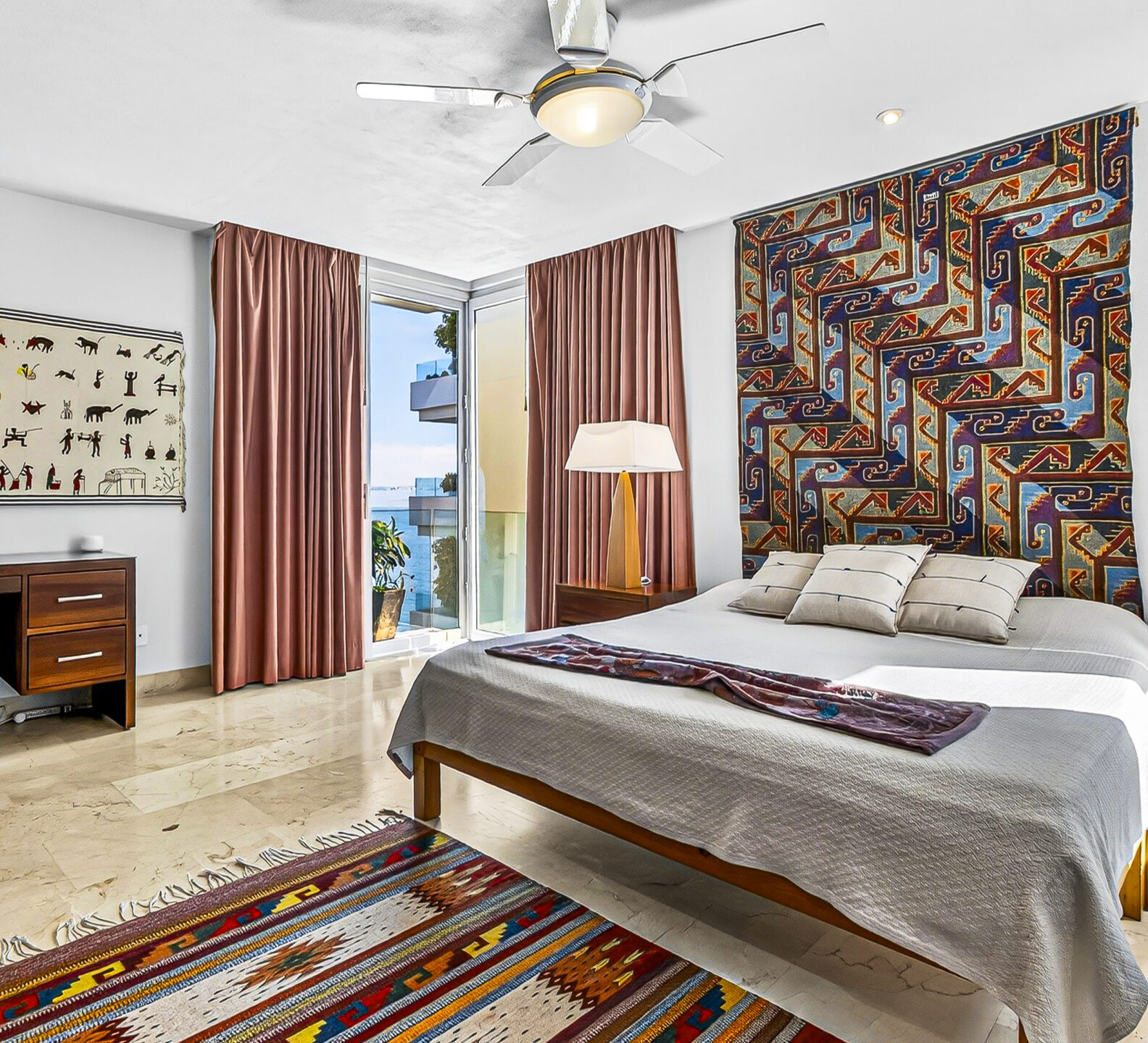 King bedroom with decorative artwork, bedside lamps, and a desk in the background.