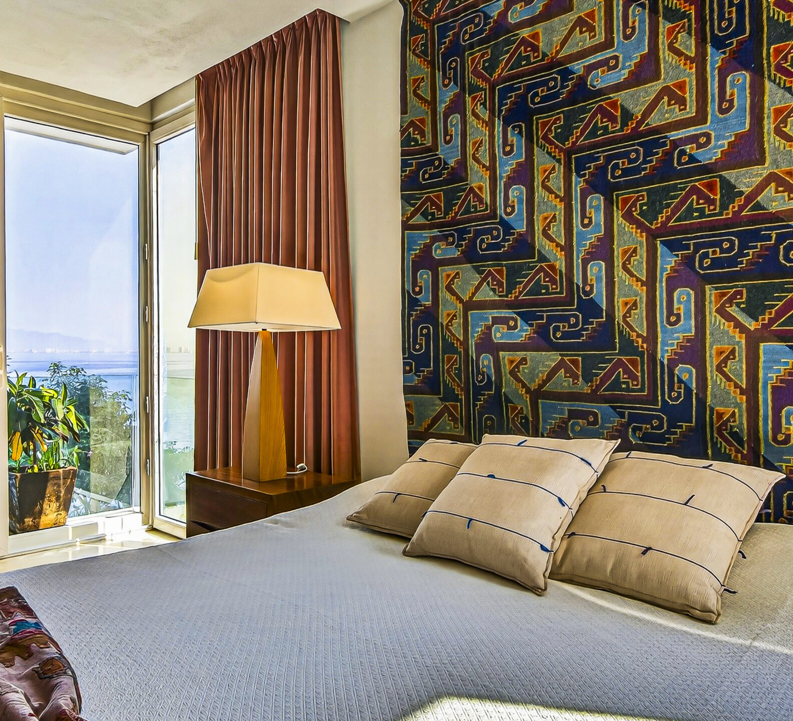 Bedroom corner with a king bed, floor-to-ceiling curtains, and partial ocean views.