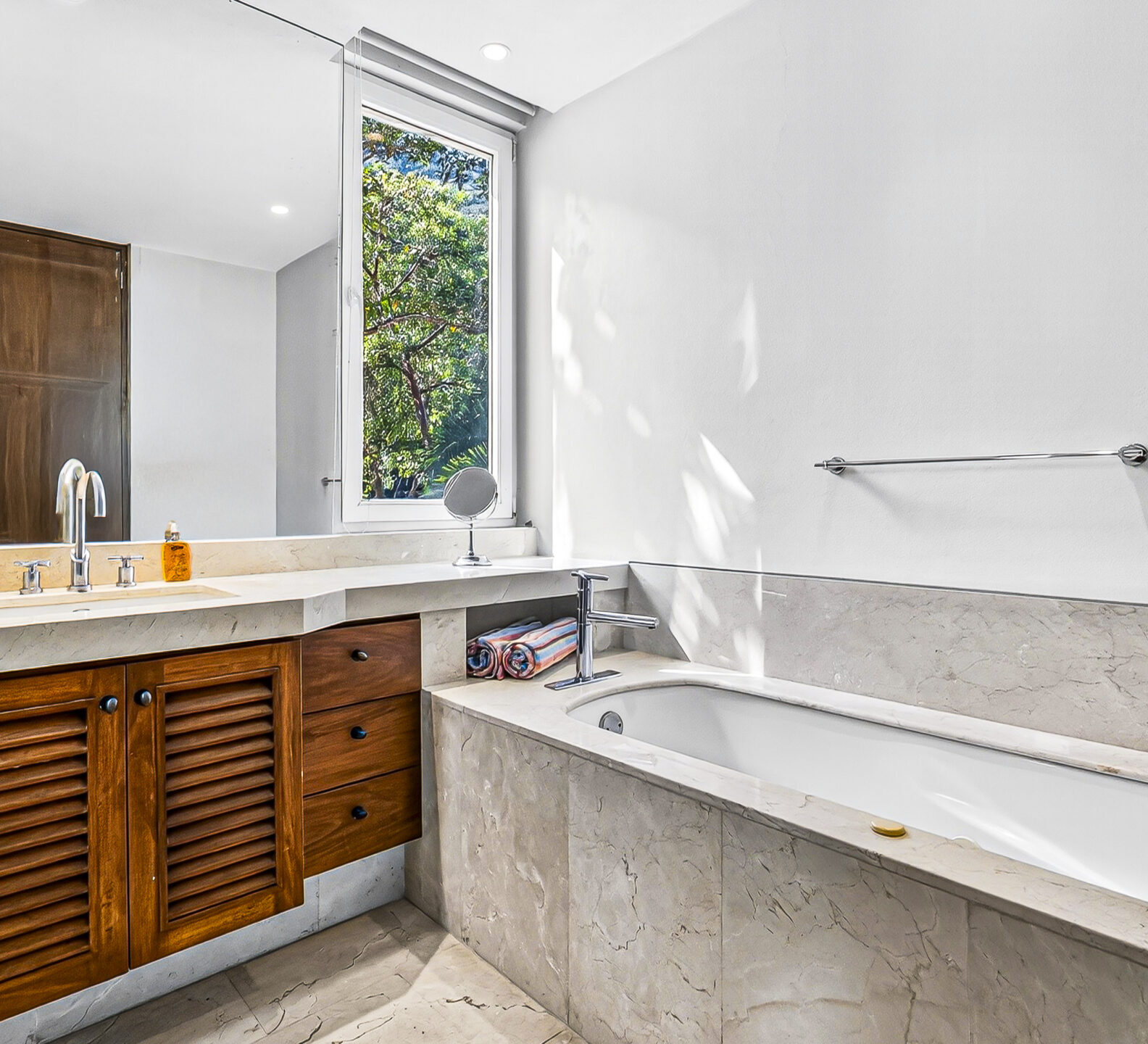 Bathroom featuring a soaking tub, double vanity, and stone finishes.