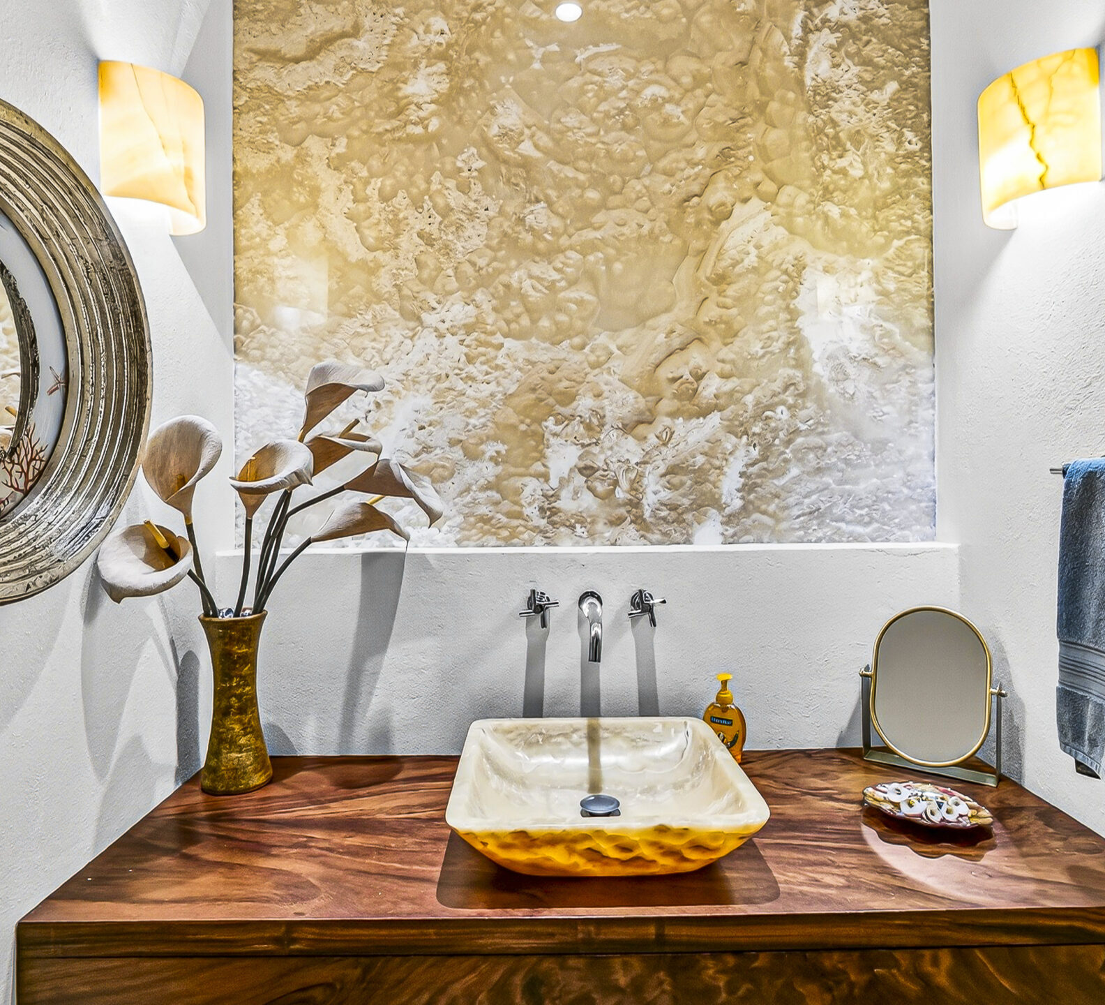 Powder room with a vessel sink, textured accent wall, and decorative mirror.