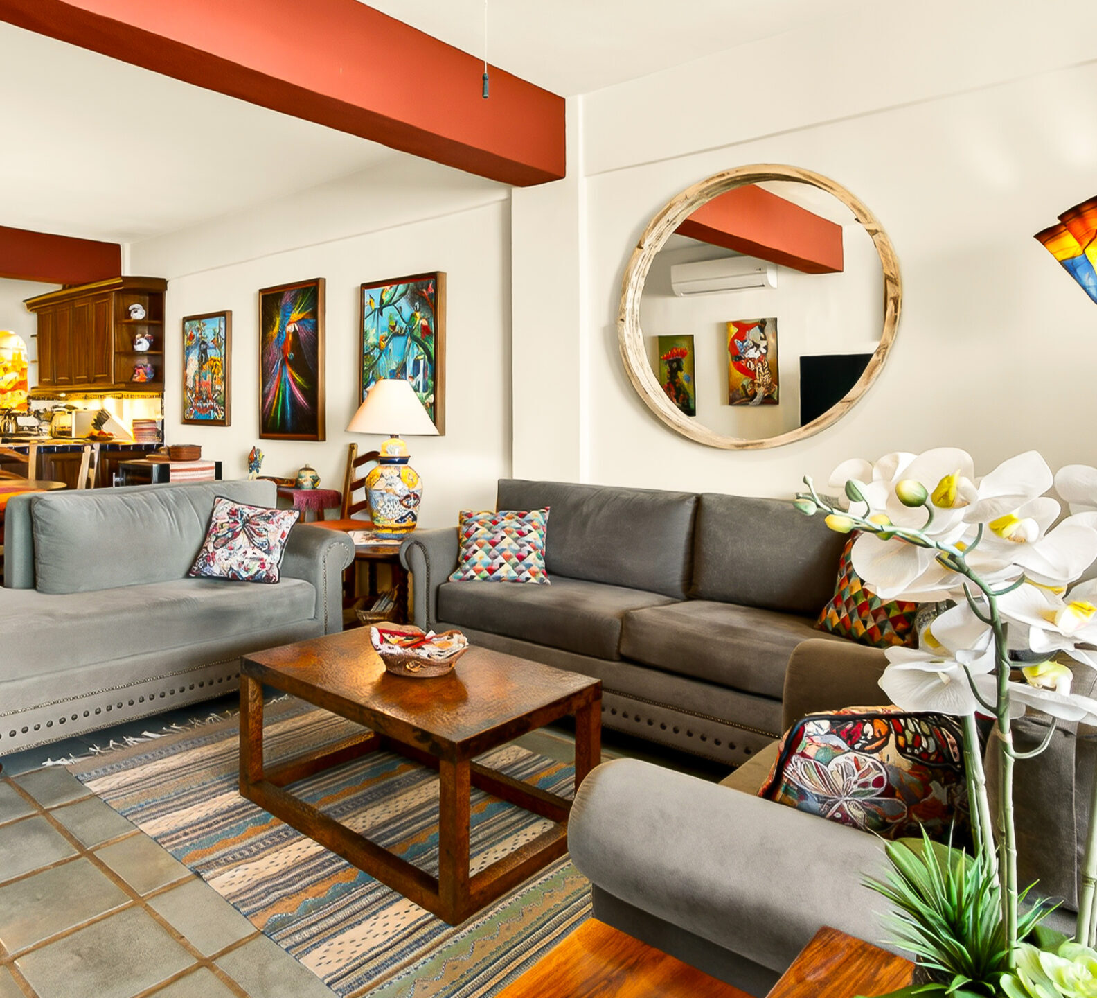 A living room arrangement with grey sectional sofas and a wooden coffee table, looking back toward the dining area and kitchen.