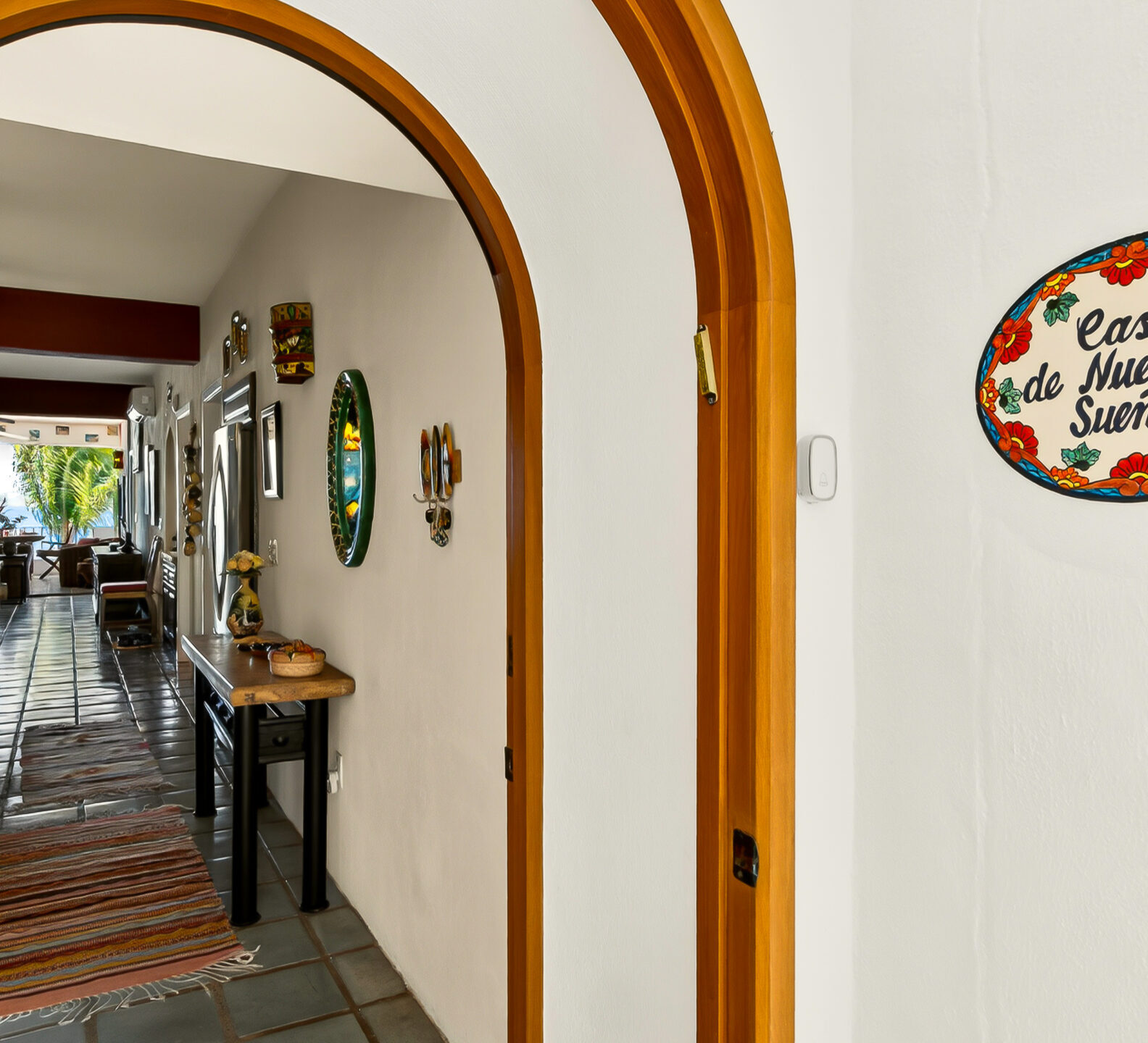 Interior hallway framed by arched wood trim, featuring decorative wall art, rustic furnishings, and a view into the open living spaces.