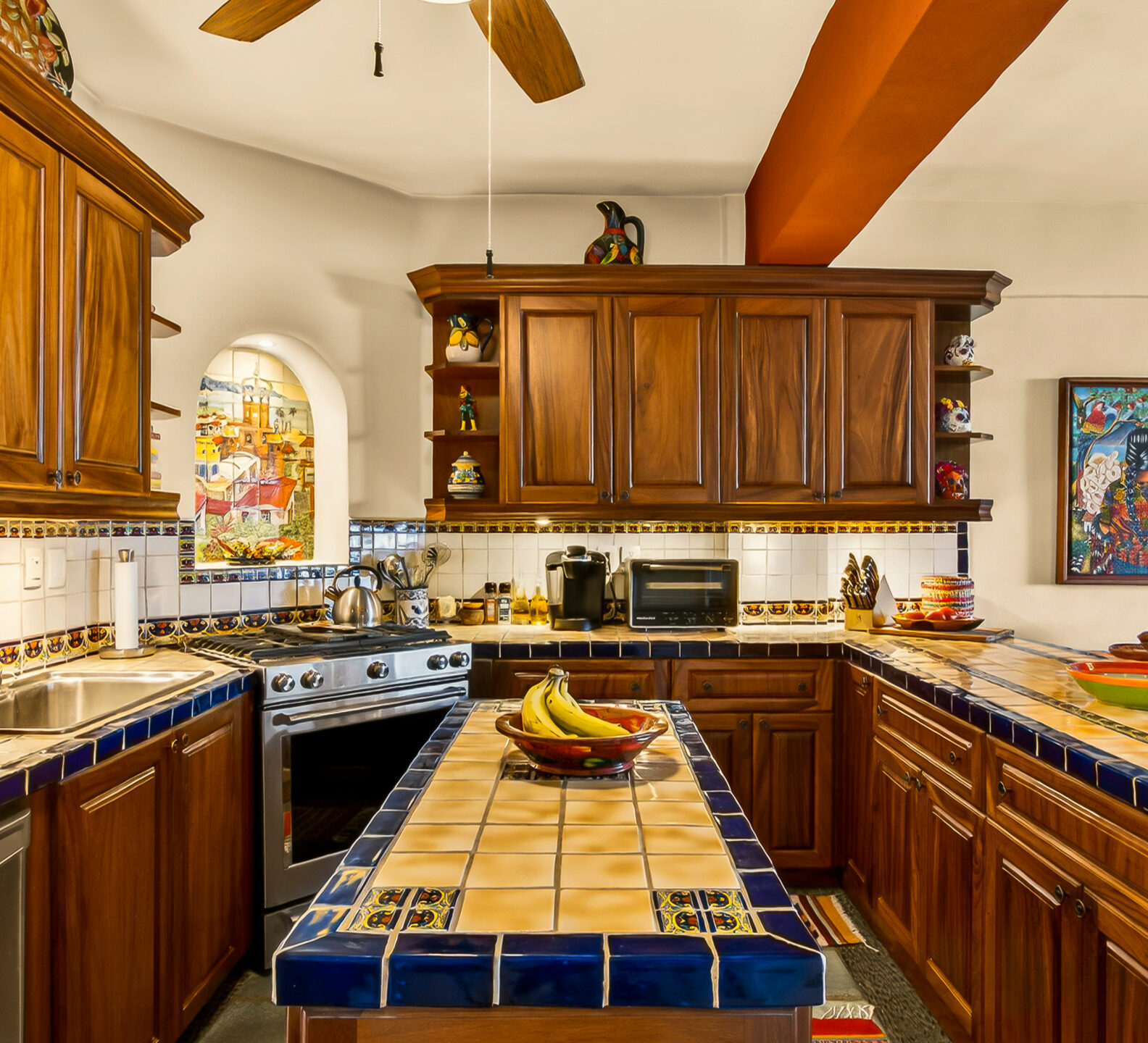 Bright kitchen with custom wood cabinetry, tiled island and countertops, exposed ceiling beams, and an open layout ideal for entertaining.